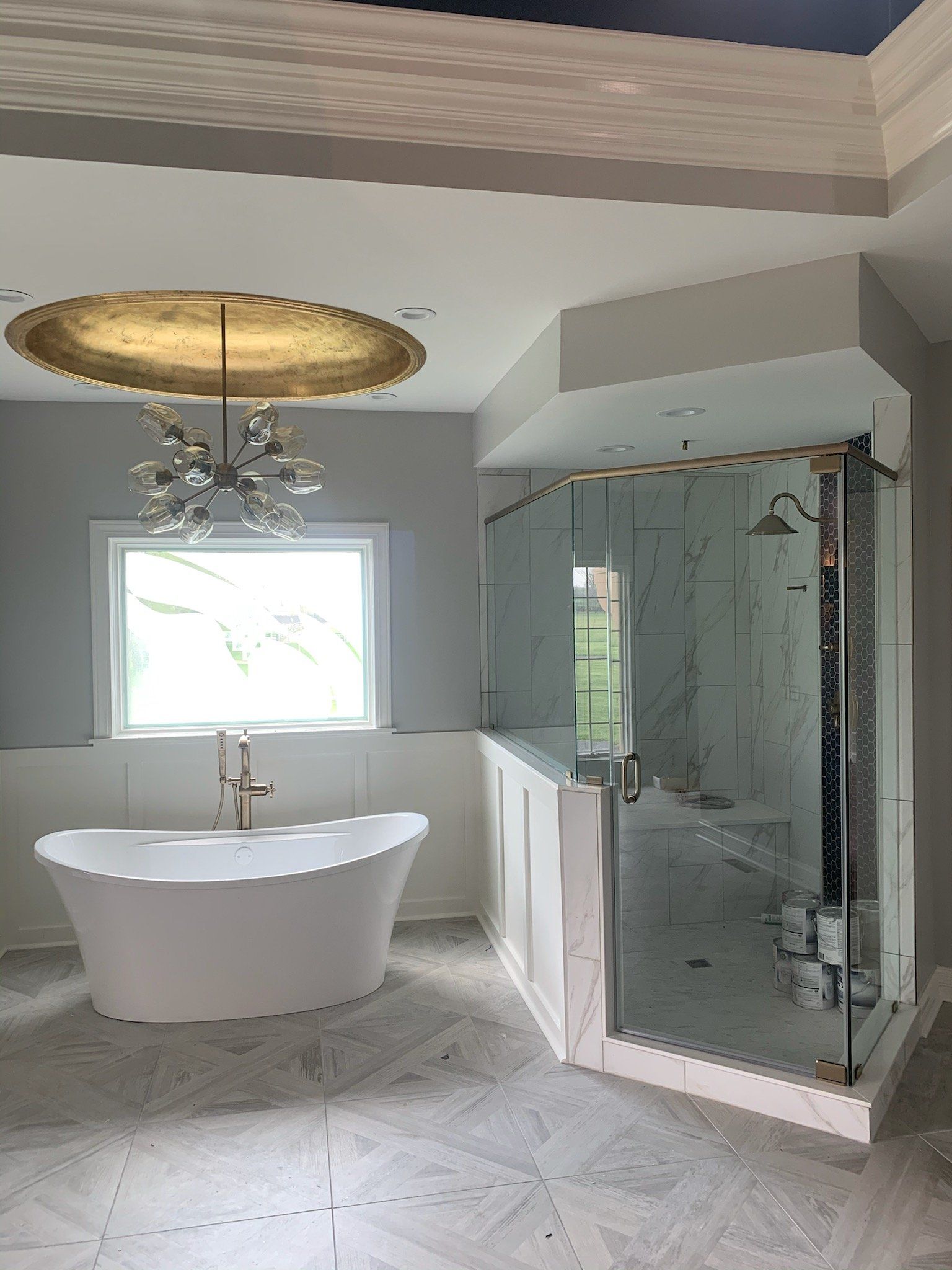 Luxurious bathroom with a white tub, glass shower, and gold accents.