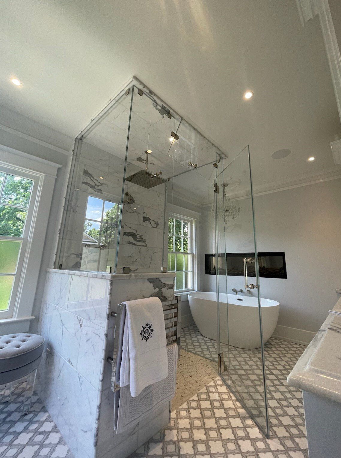 Luxurious bathroom with glass shower, freestanding tub, white tile, and natural light.