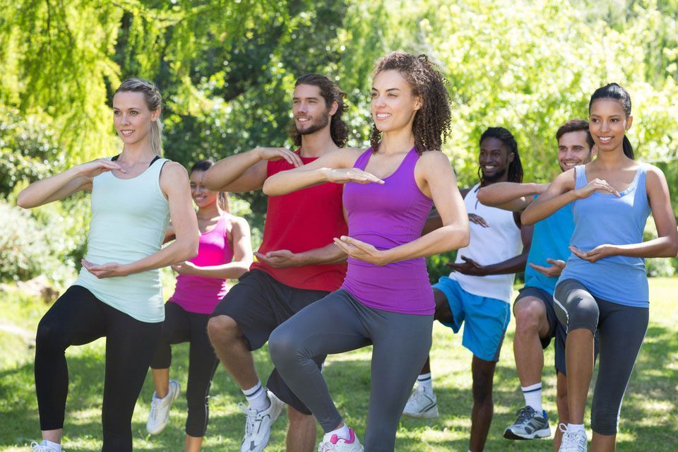 A group of people are doing exercises in a park.