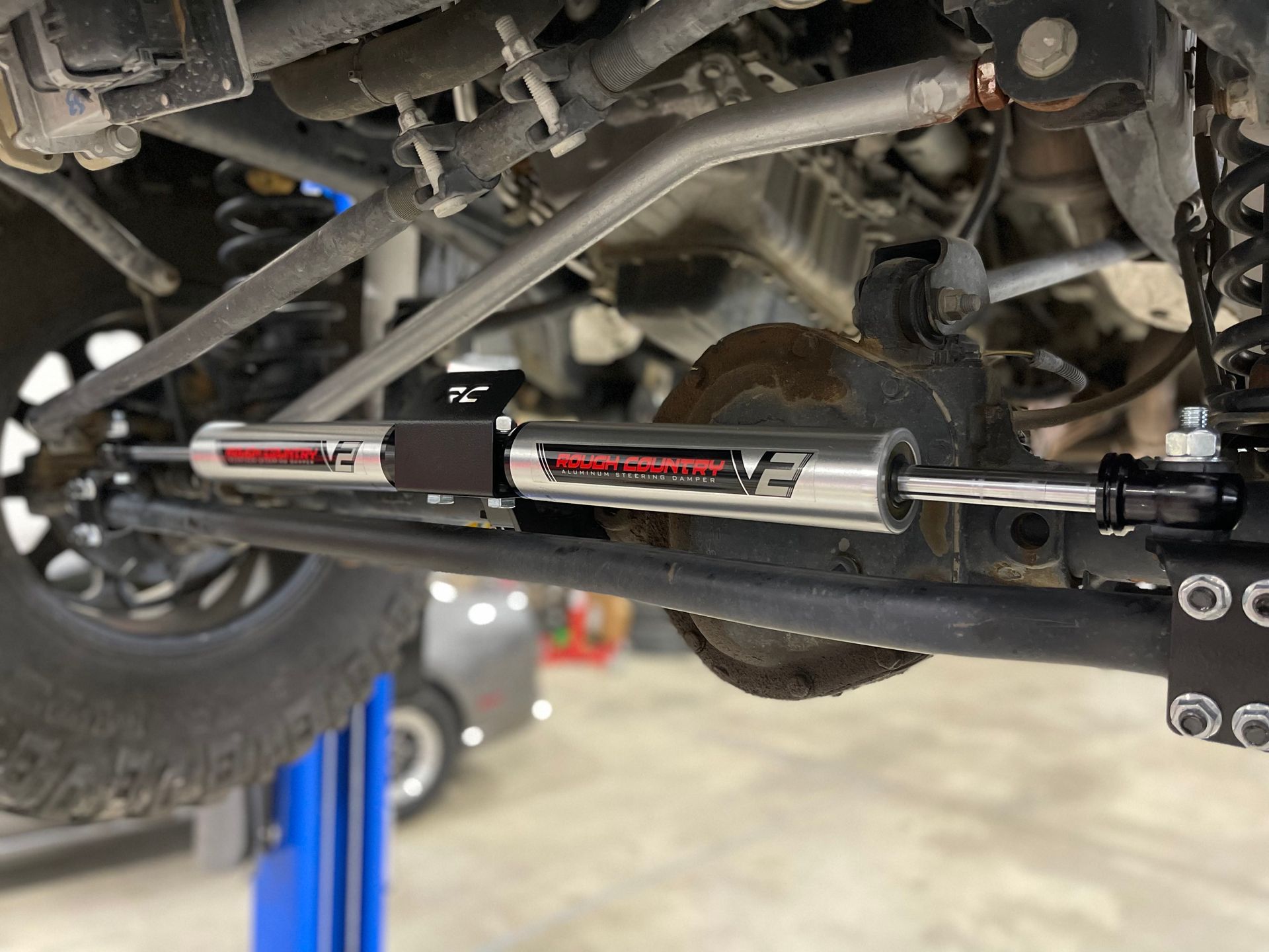 Close-up of a Jeep's front suspension with a red and silver steering stabilizer installed.