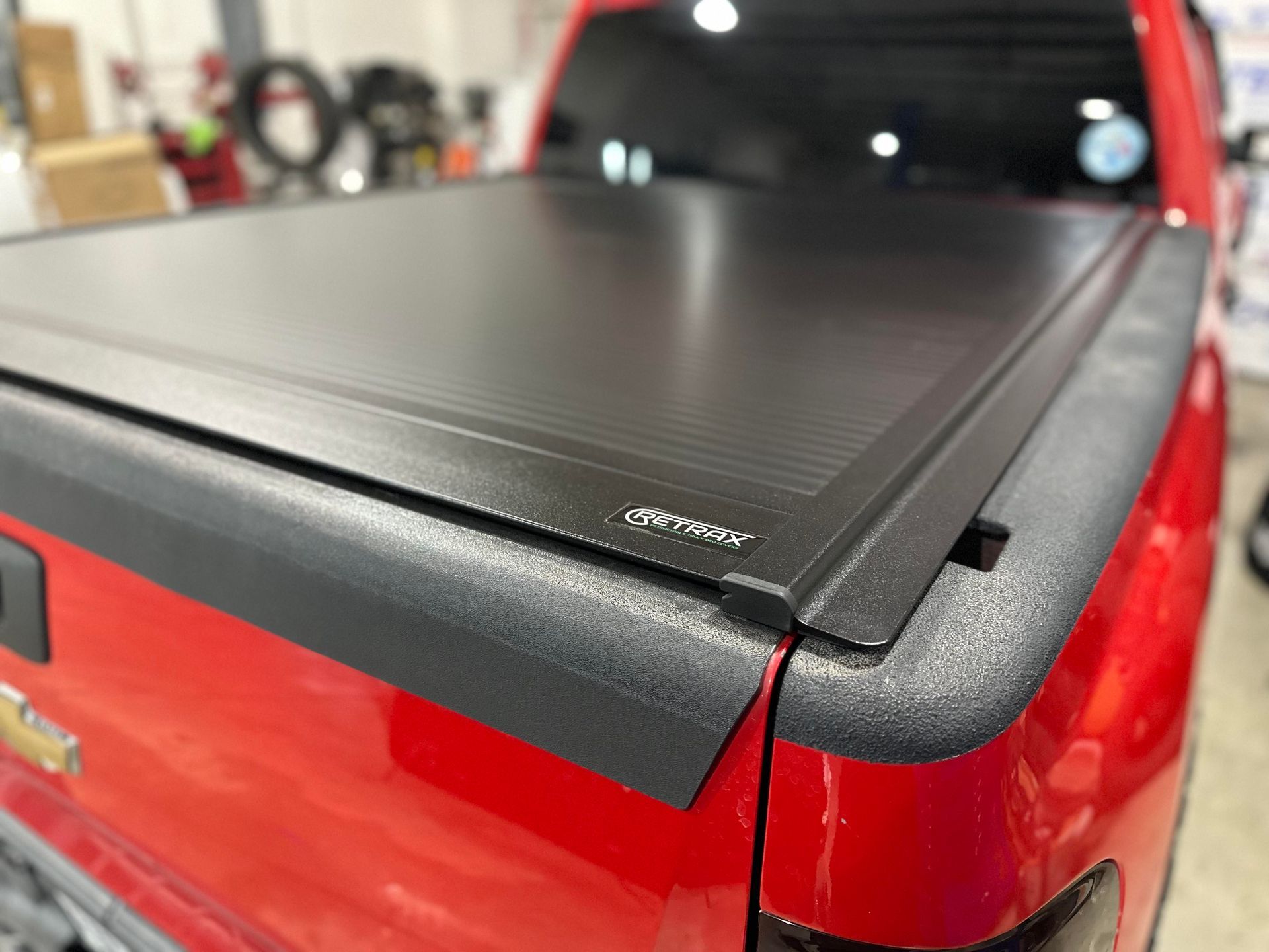 Red pickup truck bed with a black retractable tonneau cover.