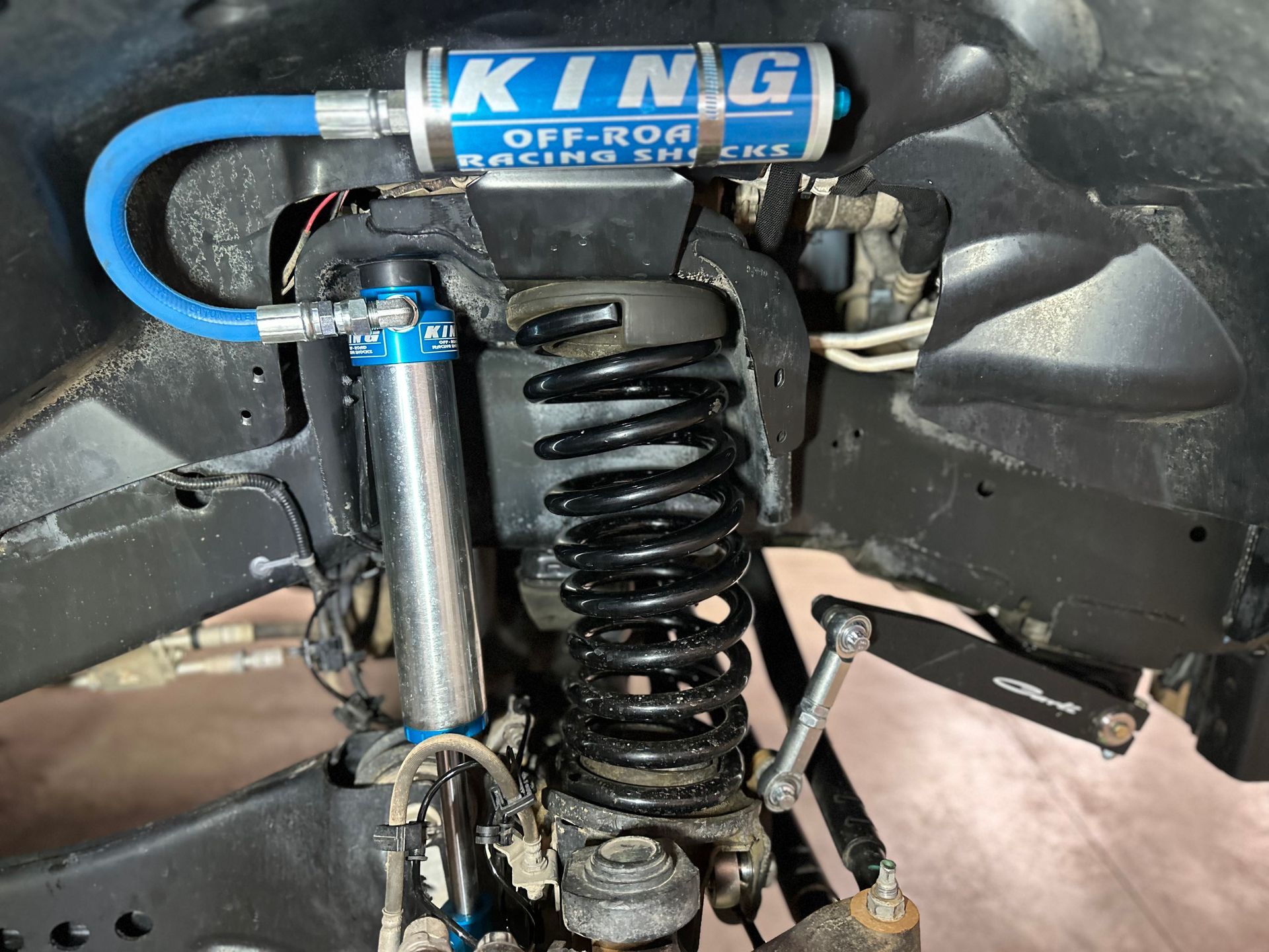 Close-up of a blue and silver King Off-Road Racing shock absorber mounted on a vehicle's suspension system.