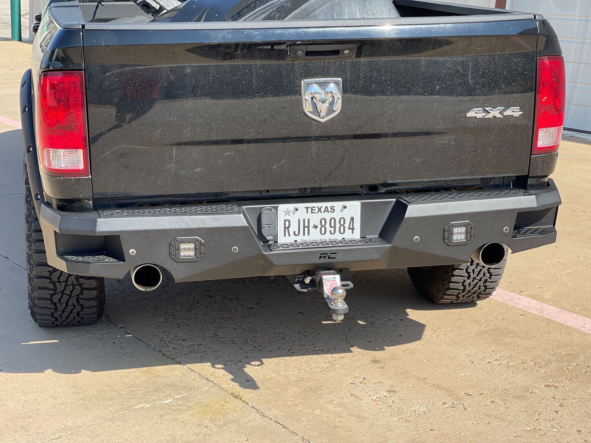 Black pickup truck with custom rear bumper, Texas license plate.