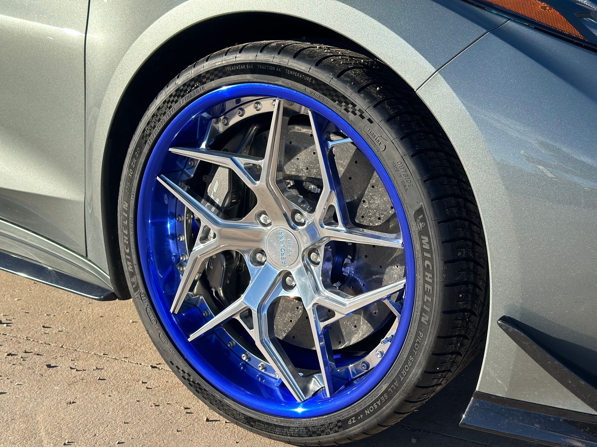 Silver car wheel with a shiny, multi-spoke design and a blue rim.