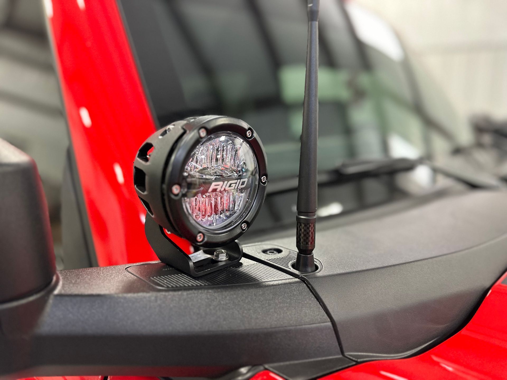 Red vehicle with black spotlight and antenna mounted on the hood.
