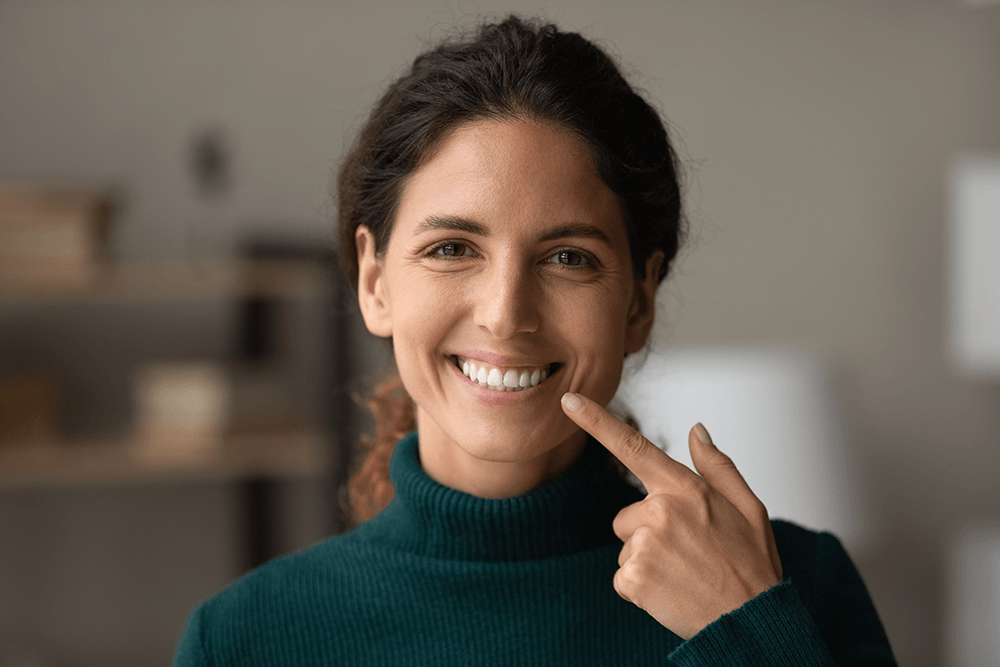 girl smiling pointing to her teeth