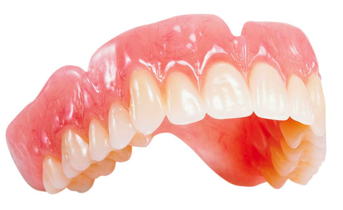 A close up of a denture on a white background.