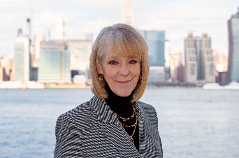A woman is standing in front of a body of water with a city skyline in the background. A woman is standing in front of a body of water with a city skyline in the background.