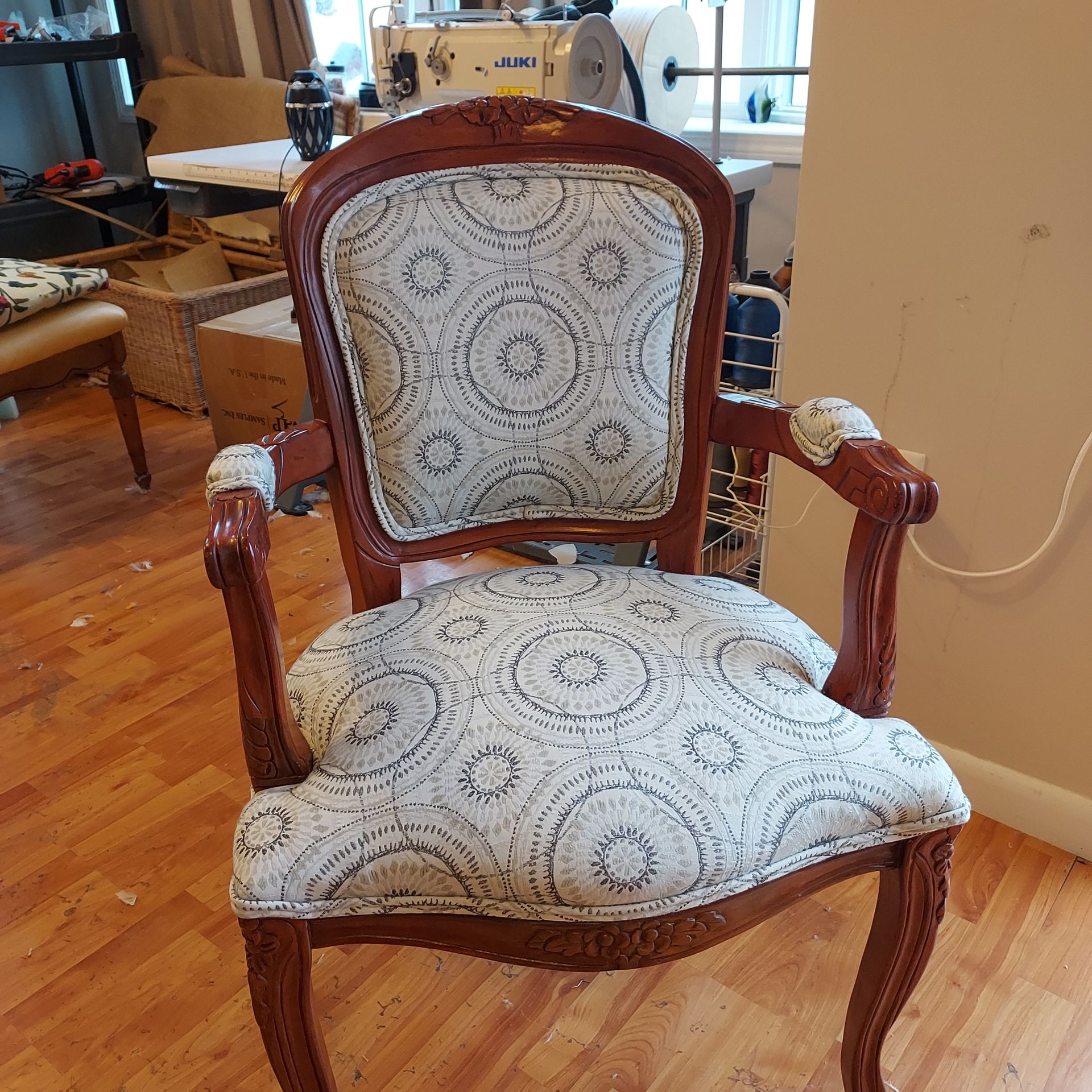 A chair with wooden armrests is sitting on a concrete floor.