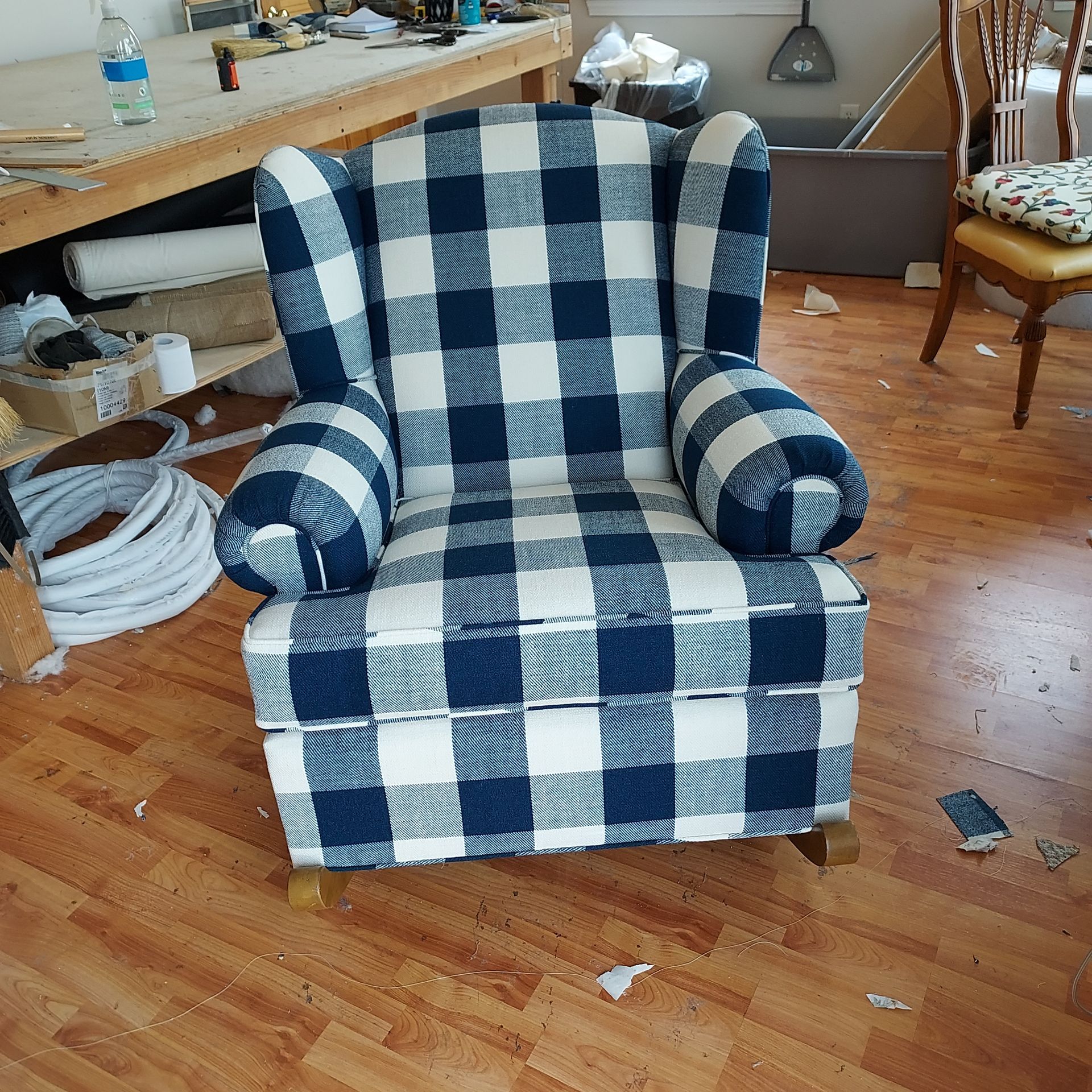 A blue and white plaid chair is sitting on a wooden floor