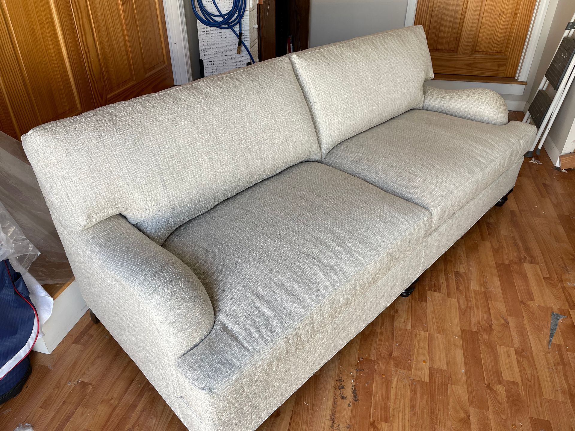 A white couch is sitting on a wooden floor in a room.