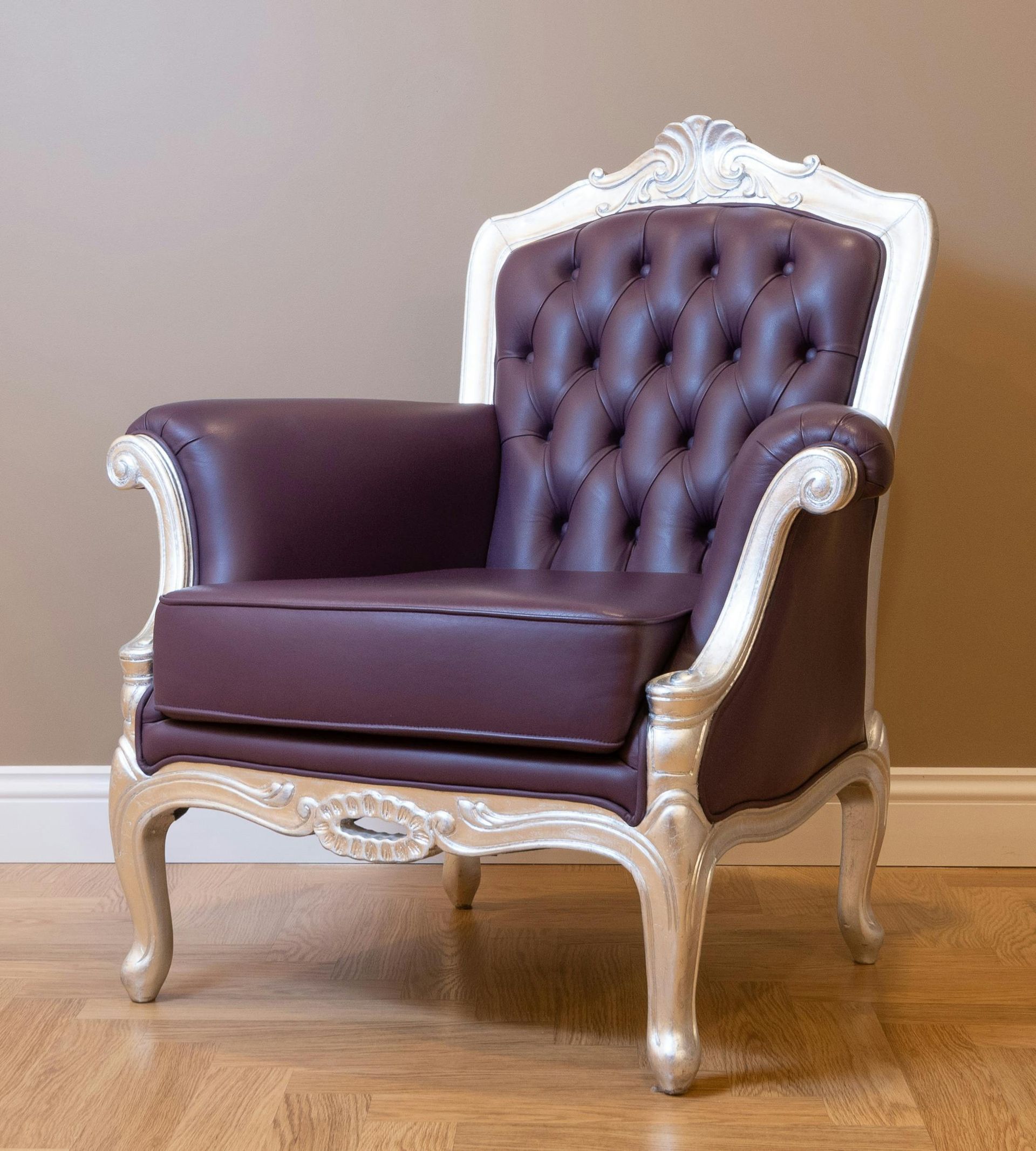 A brown leather chair with white trim is sitting on a wooden floor.