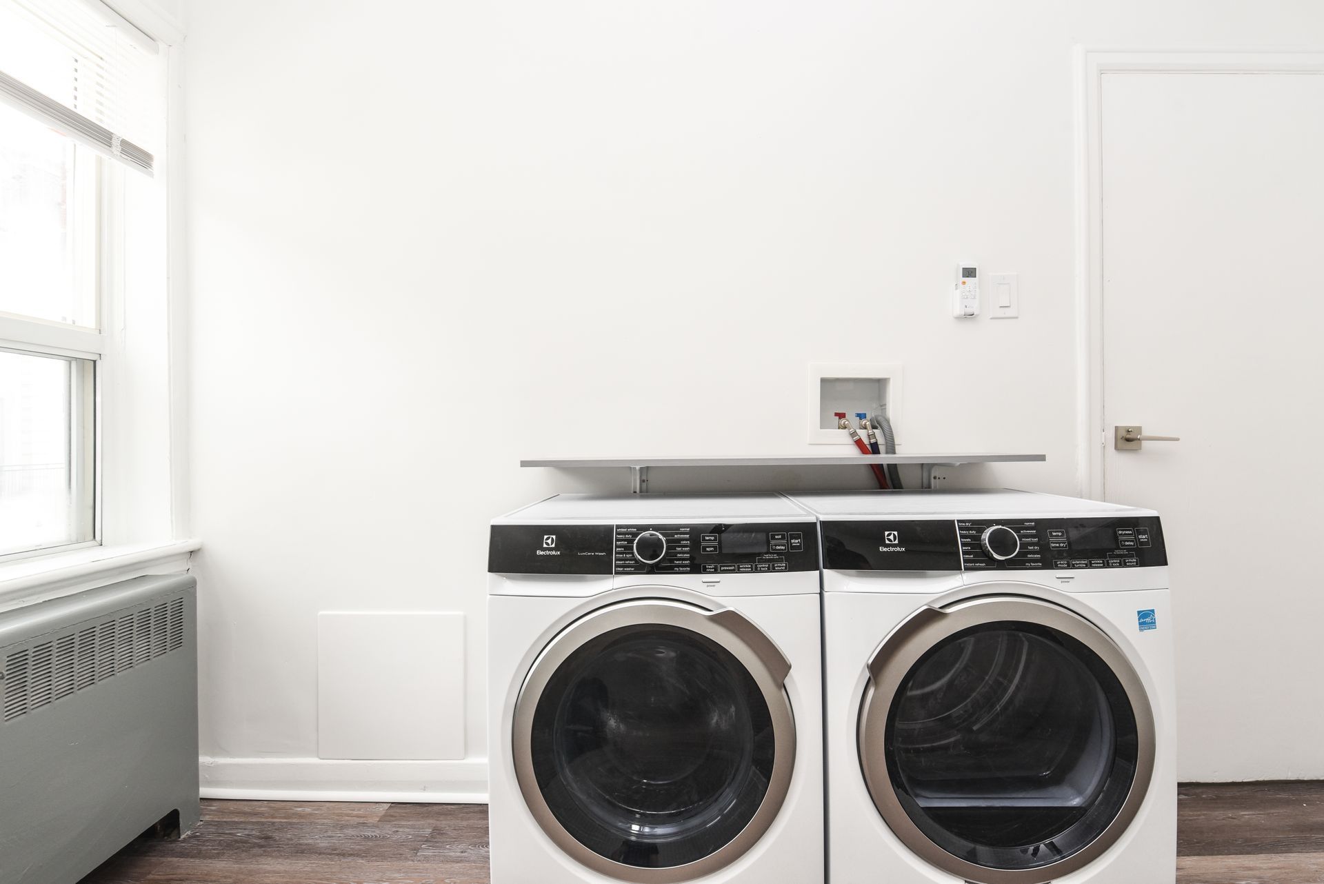 Laundry room with white walls, window, and two front-loading washer and dryer units.