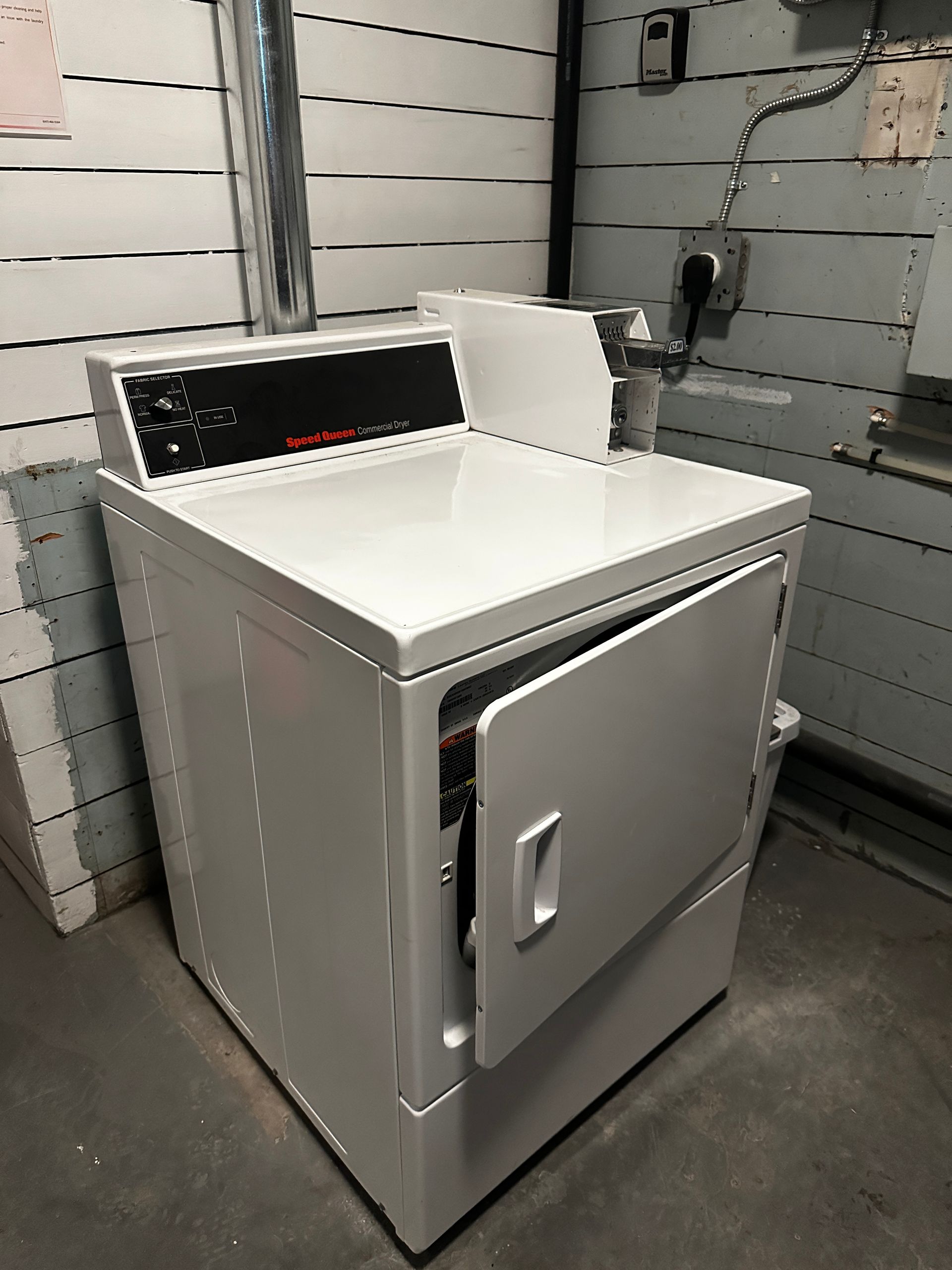 White utility sink cabinet with a metal door in a workshop or garage setting