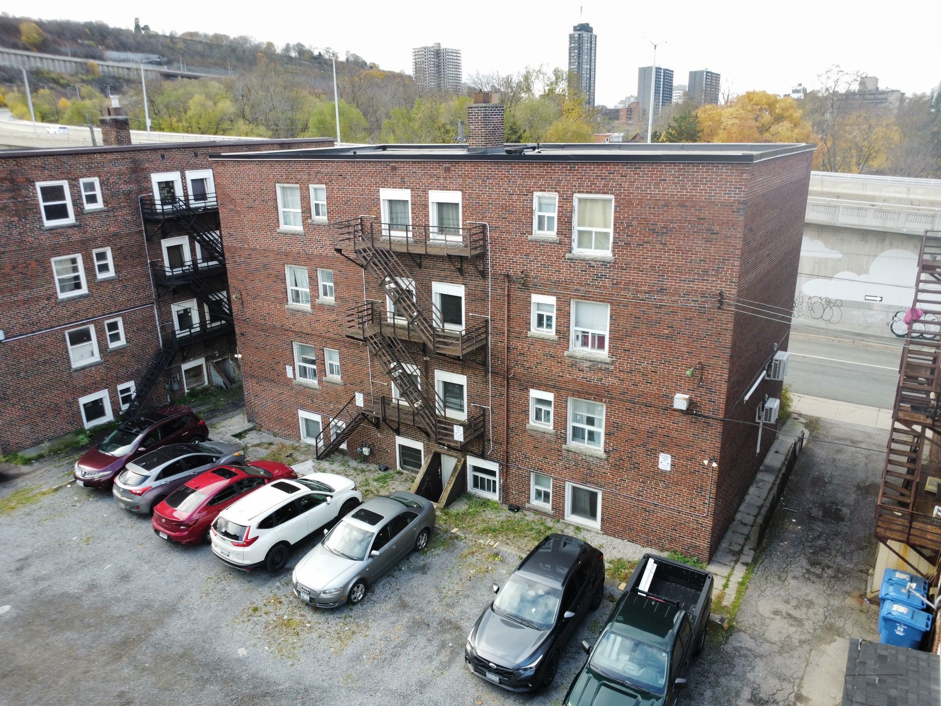Brick apartment courtyard with parked cars and an overcast sky