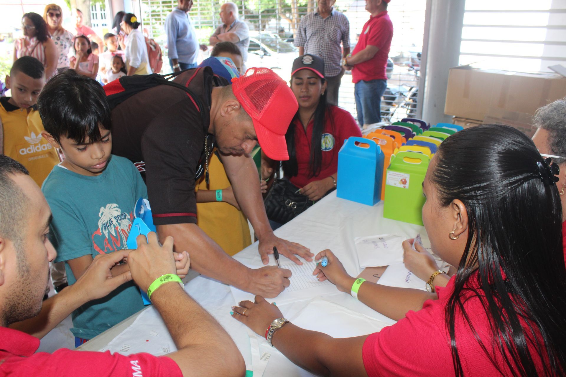 People gathered around a table, filling out forms at a community event.