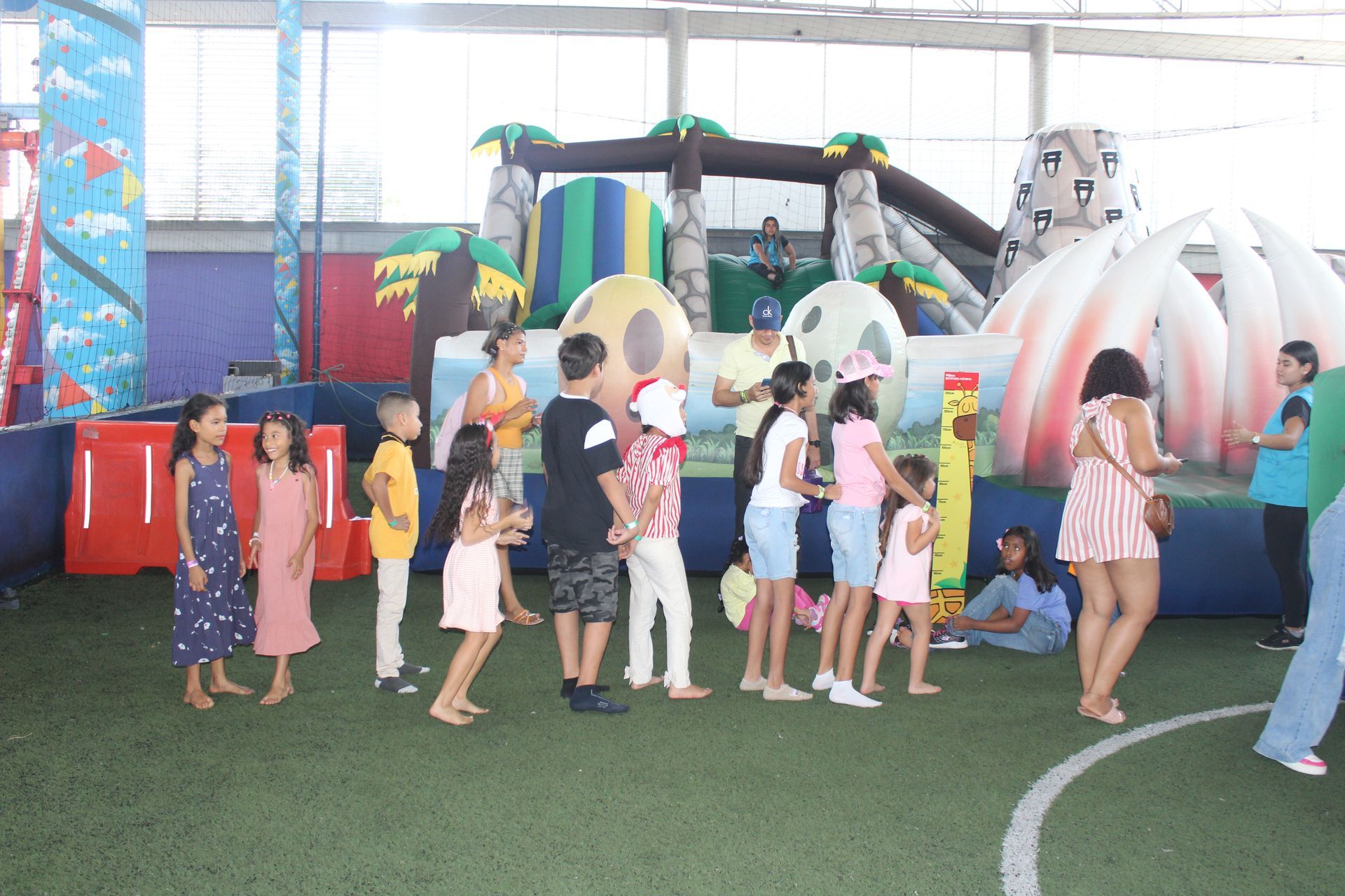 Children standing in line at an indoor play area with colorful inflatable slides and tunnels
