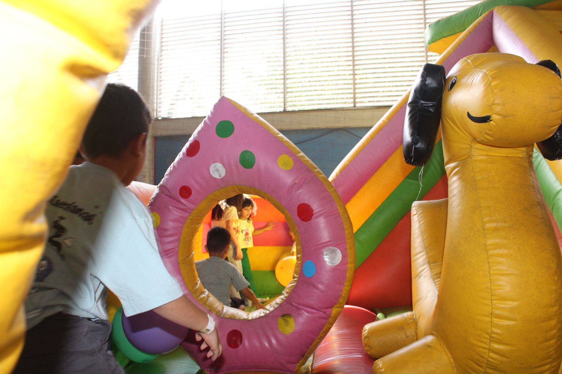 Child playing inside colorful inflatable bounce house with pink, yellow, and rainbow features