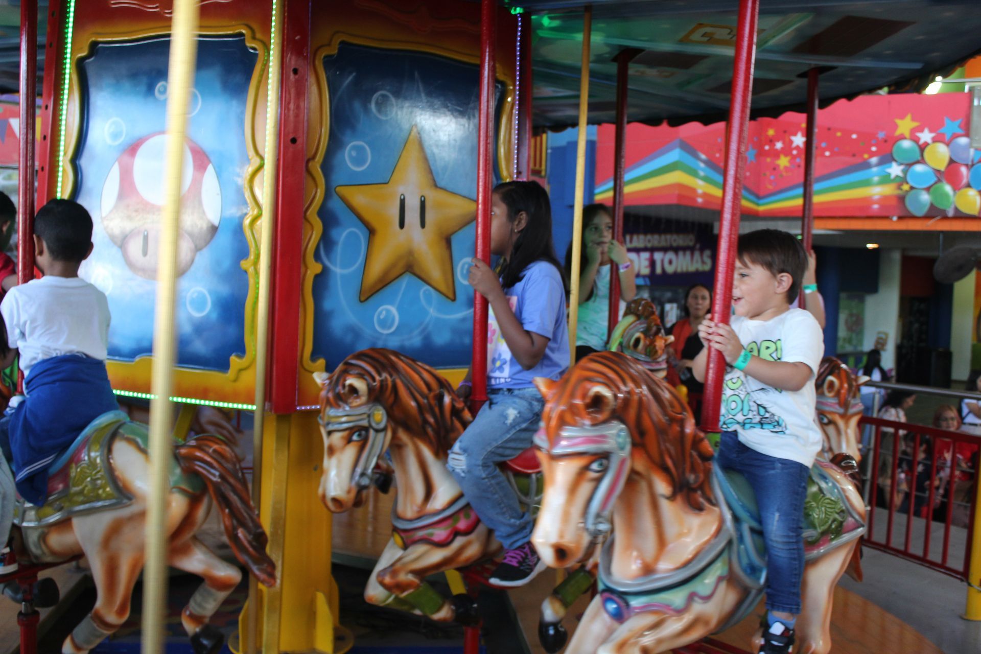 Children riding horses on a colorful carousel at an amusement park