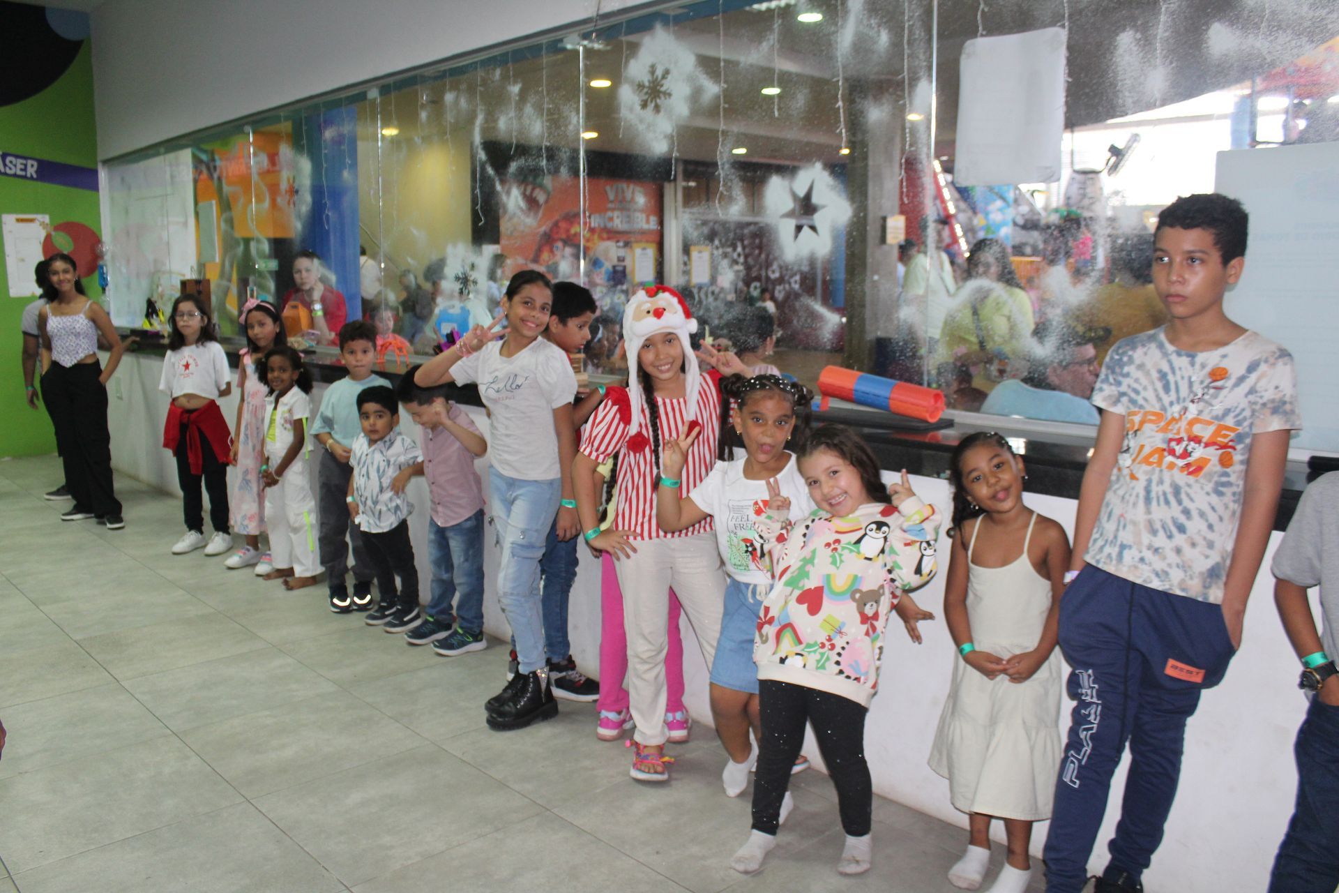 Children standing in a line indoors, holding hands in a bright hallway with colorful wall art
