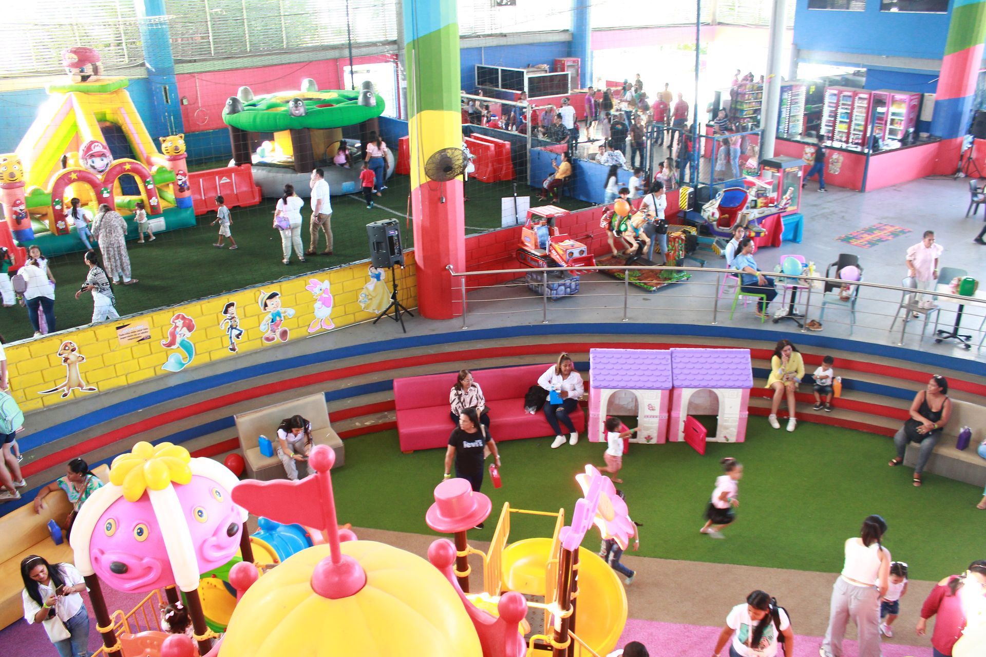 Indoor children’s play area with colorful play structures and families seated around the room