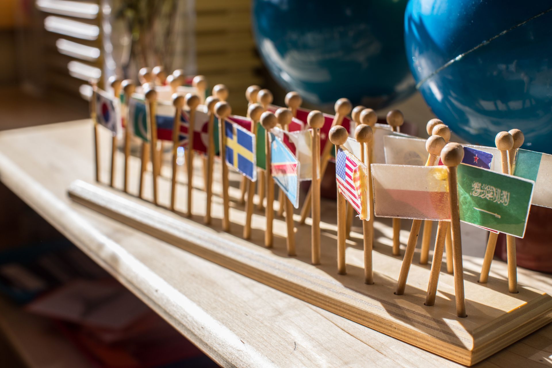 Small wooden figures holding flags in a row on a display board, including Sweden and Saudi Arabia.