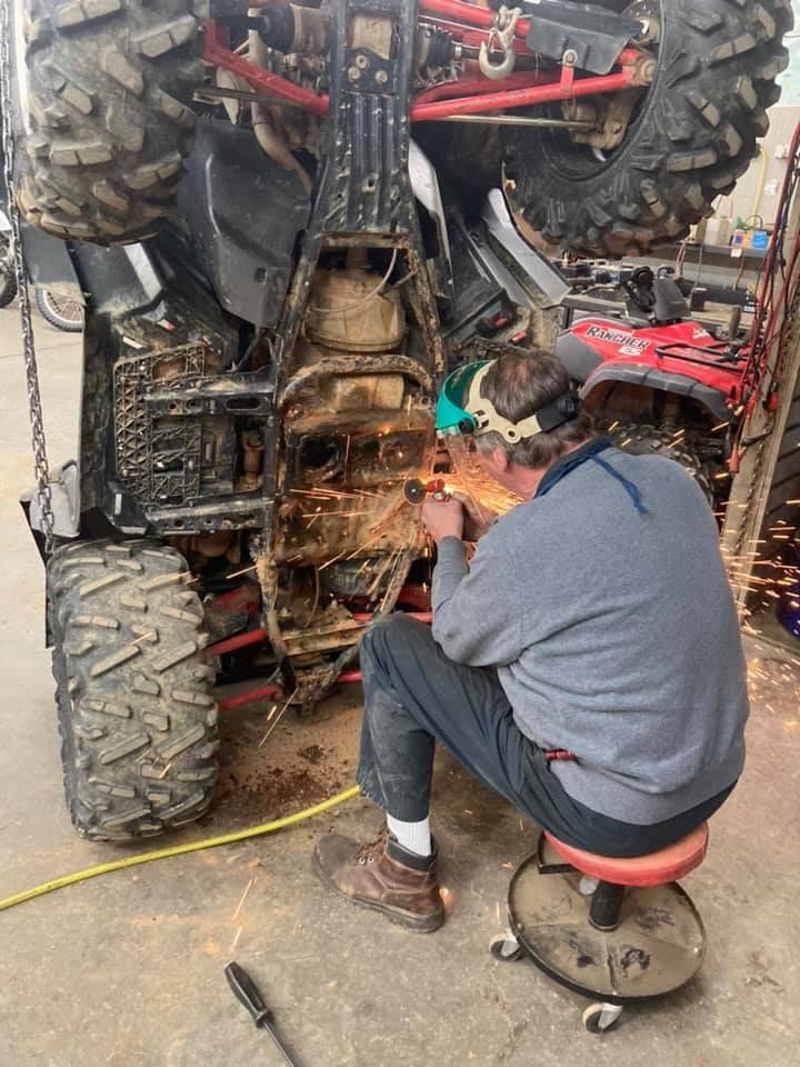 A man is welding a four wheeler in a garage.