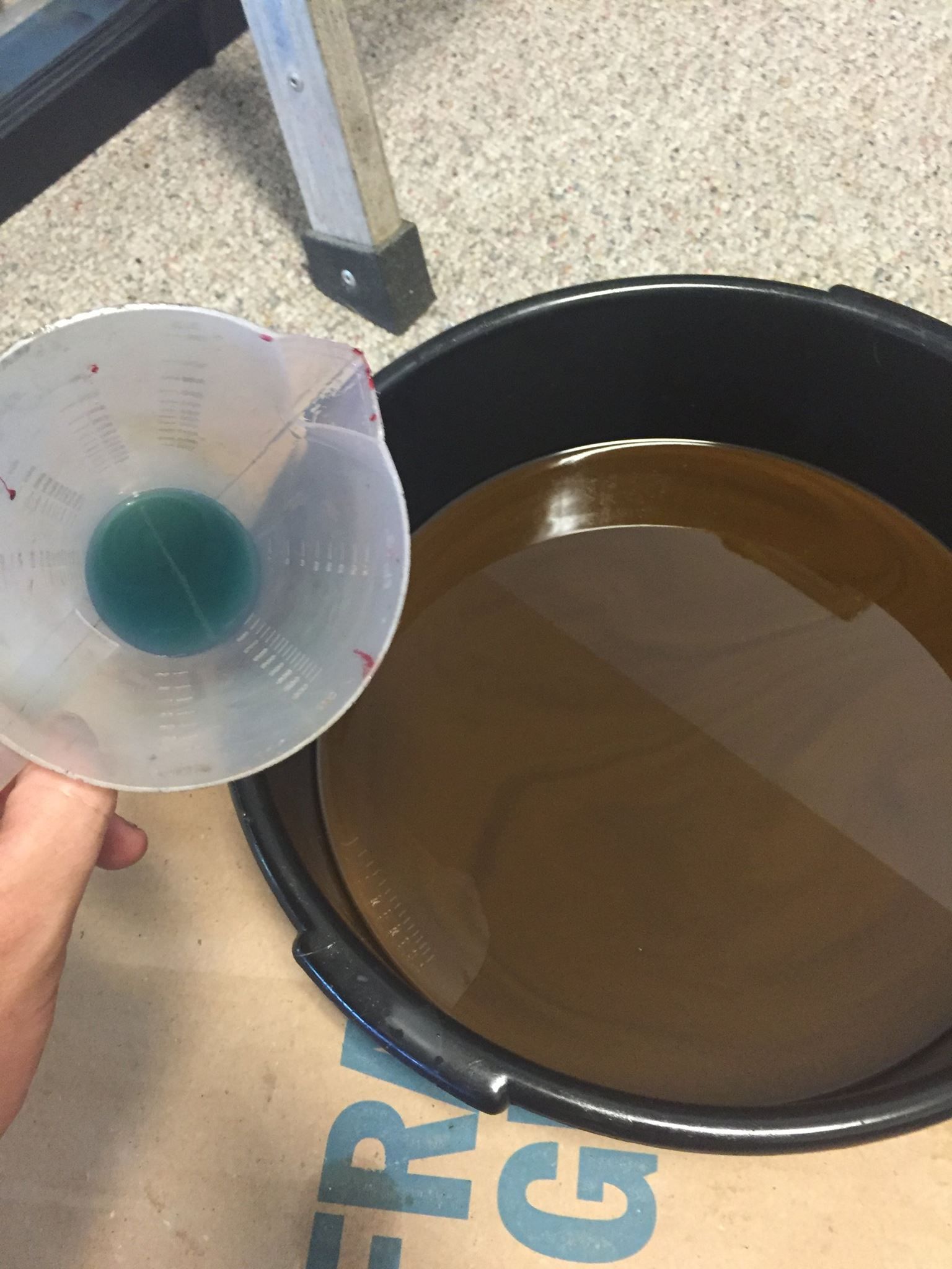 A person is pouring liquid from a funnel into a bucket