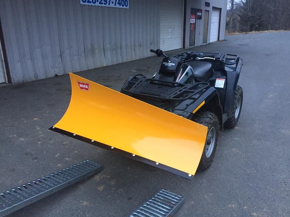 An atv with a yellow plow attached to it