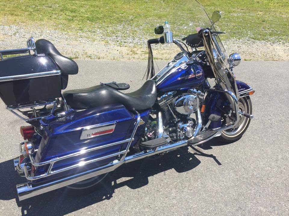 A blue harley davidson motorcycle is parked on the side of the road.