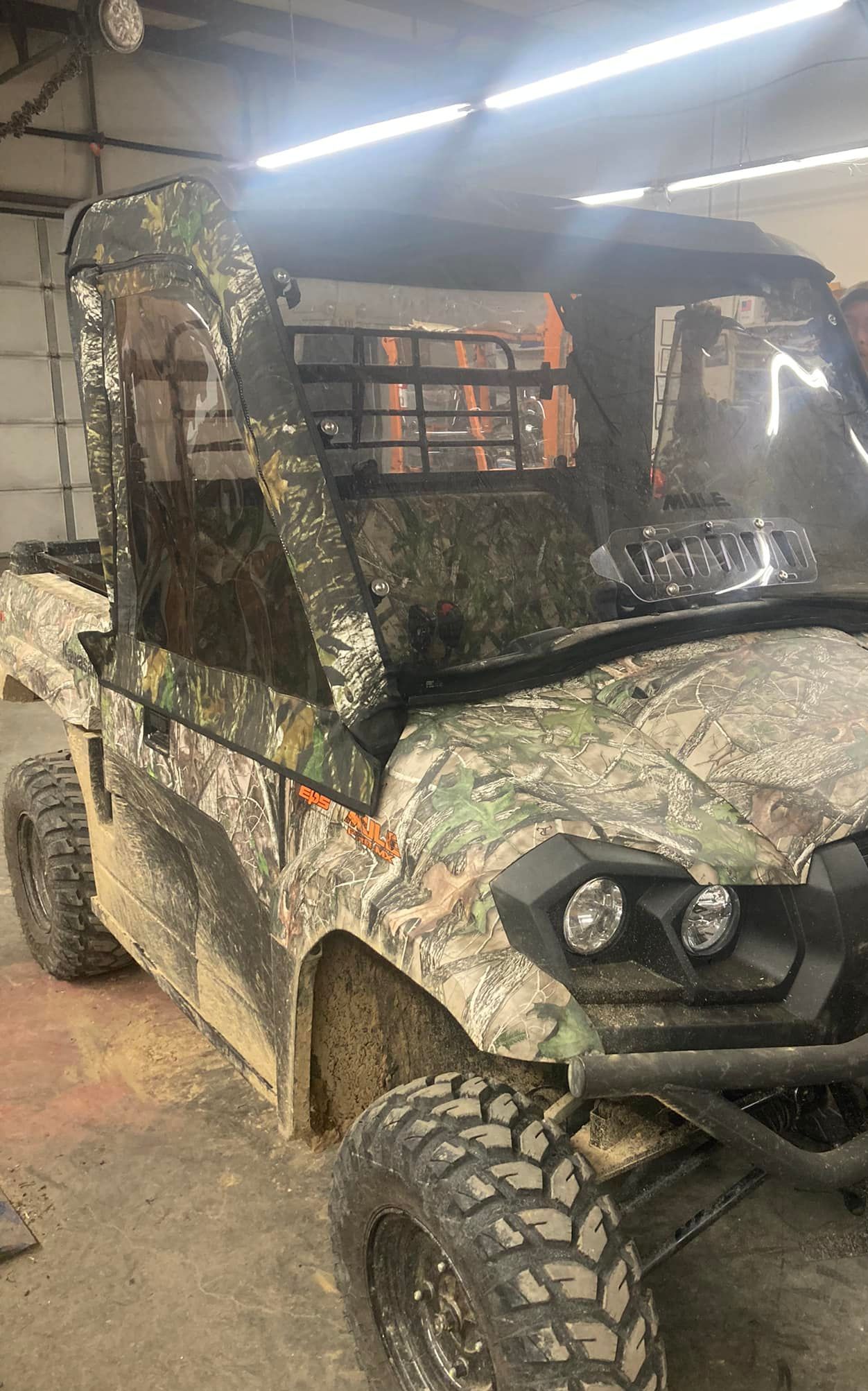 A muddy utility vehicle is parked in a garage.