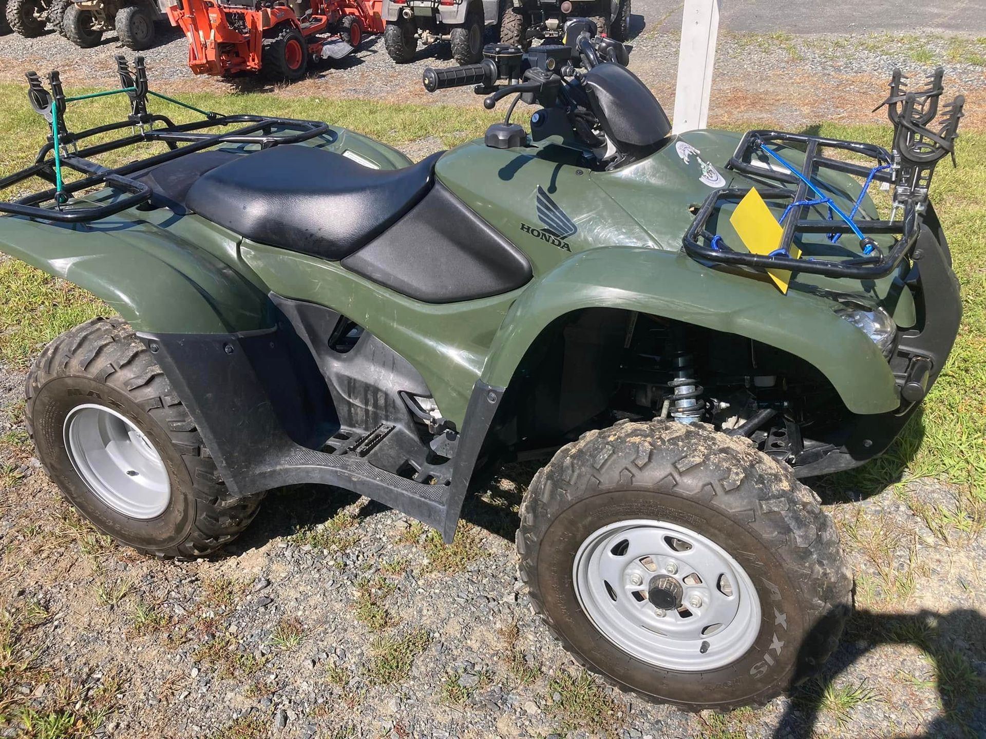 A green atv is parked on a gravel road.