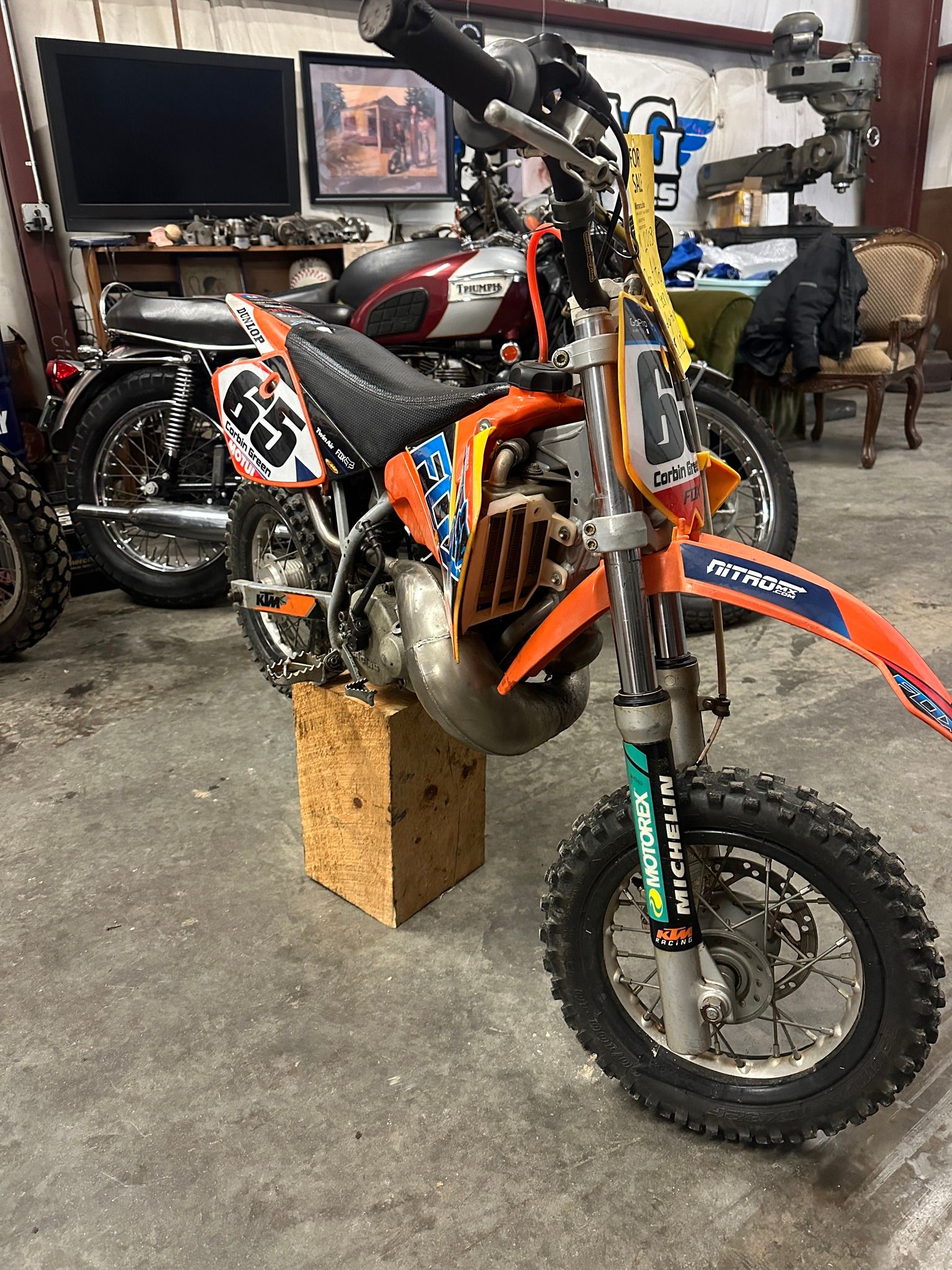 A dirt bike is sitting on top of a wooden block in a garage.