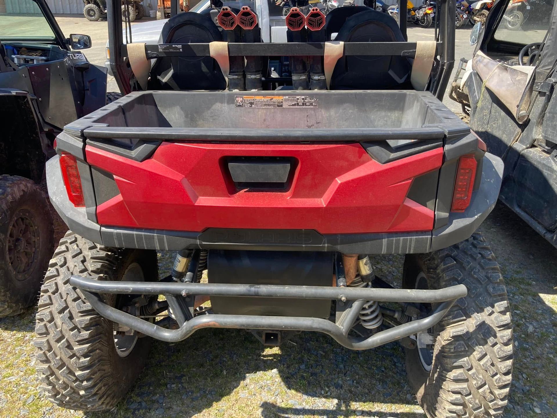 A red atv is parked in a lot with other atvs.