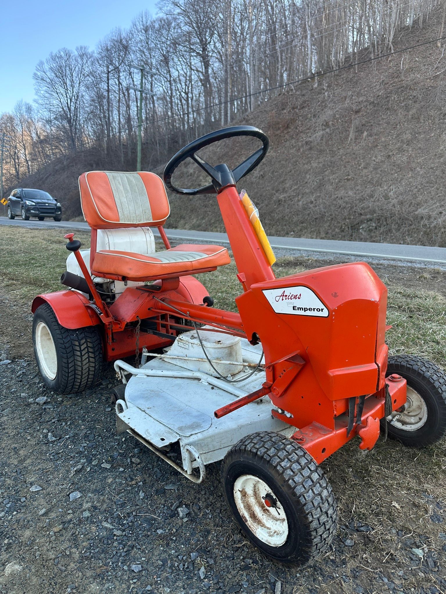 A red and white lawn mower is parked on the side of the road.