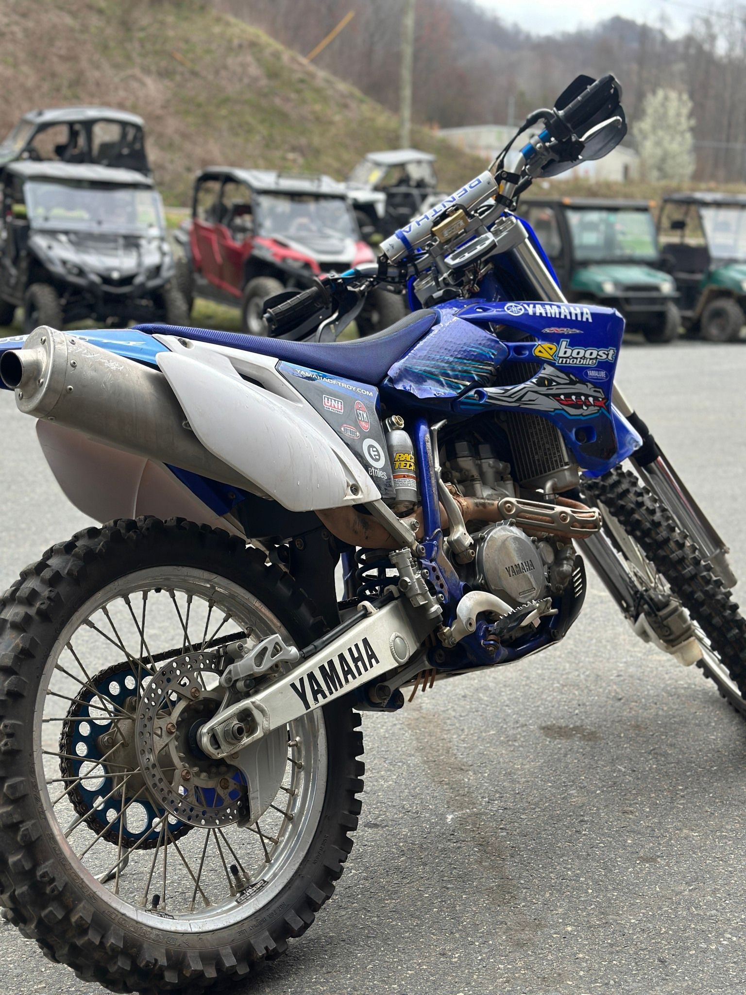 A blue and white dirt bike is parked in a parking lot.