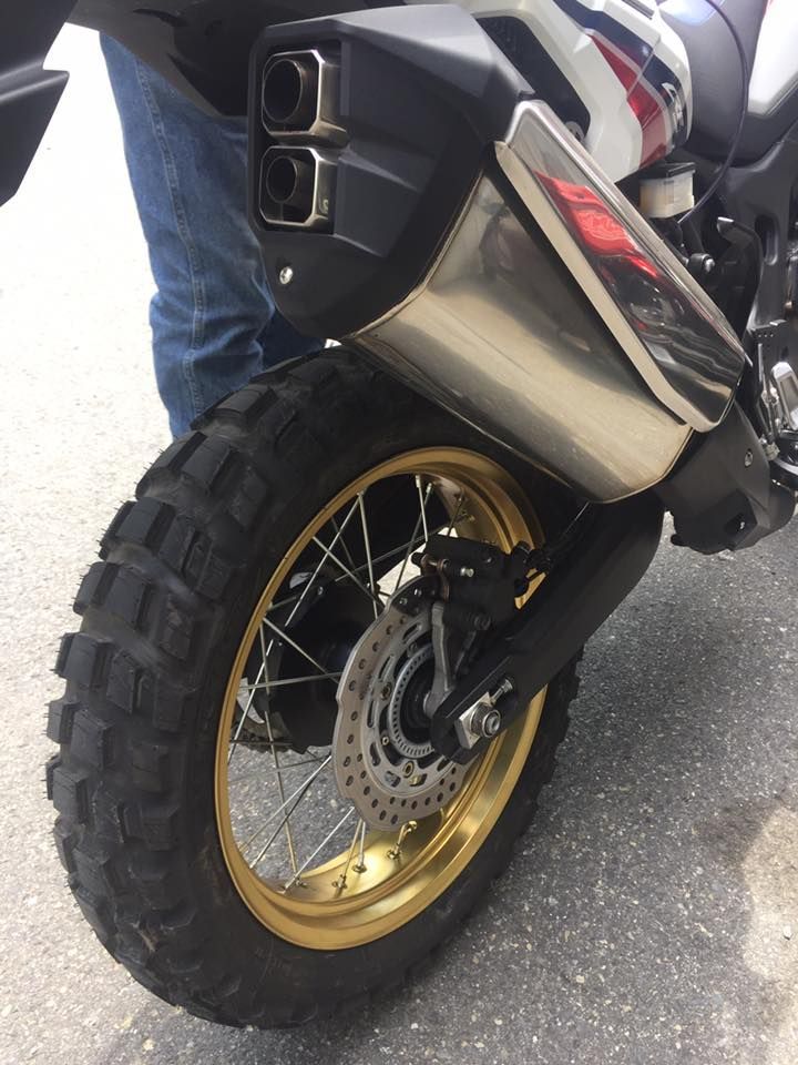 A person is standing next to a motorcycle with a large tire