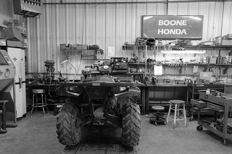 A black and white photo of a honda atv in a garage.