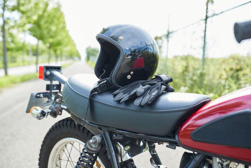 A motorcycle with a helmet and gloves on the seat.
