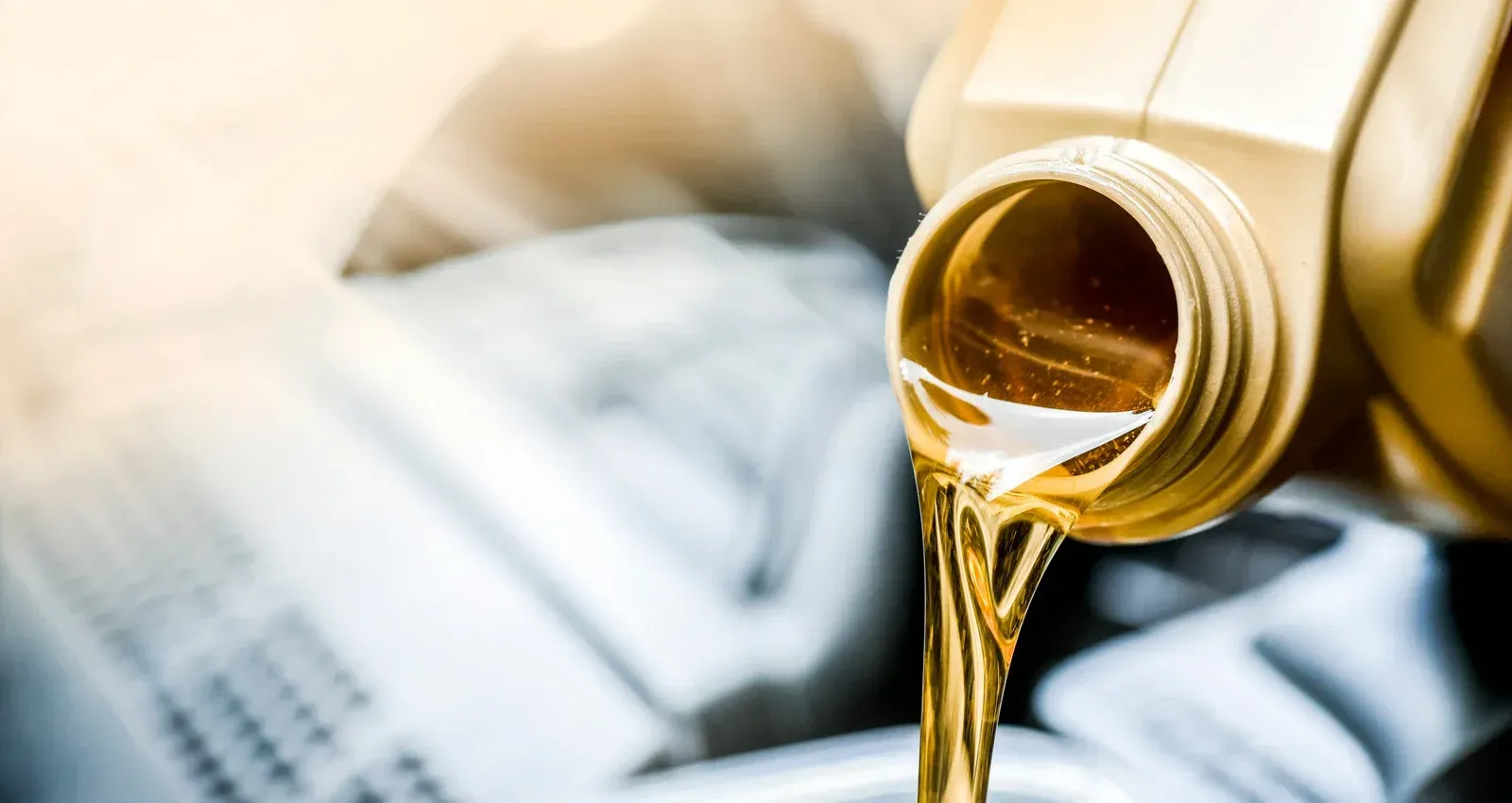 A bottle of oil is being poured into a cup.