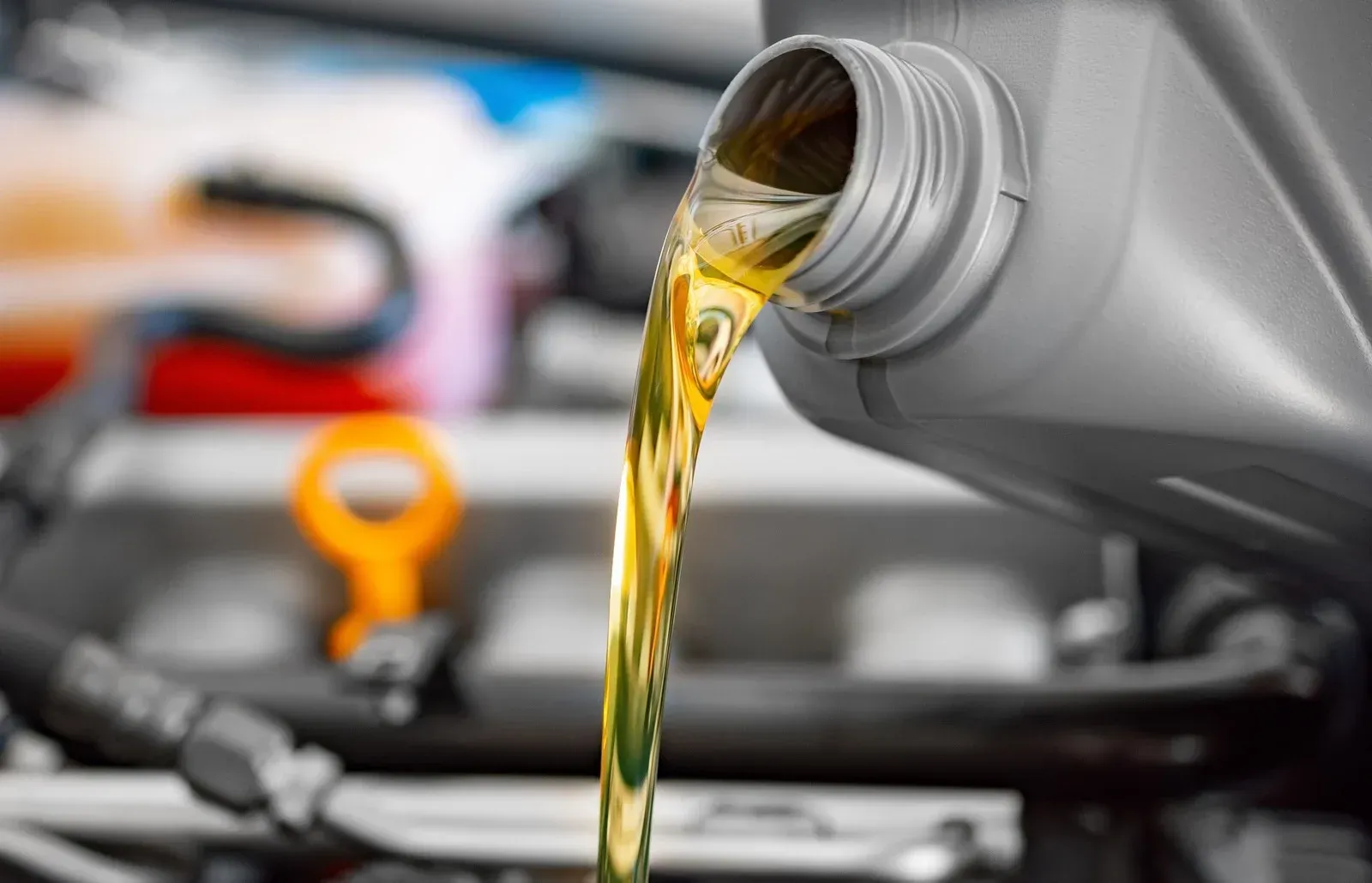 A bottle of oil is being poured into a car engine.