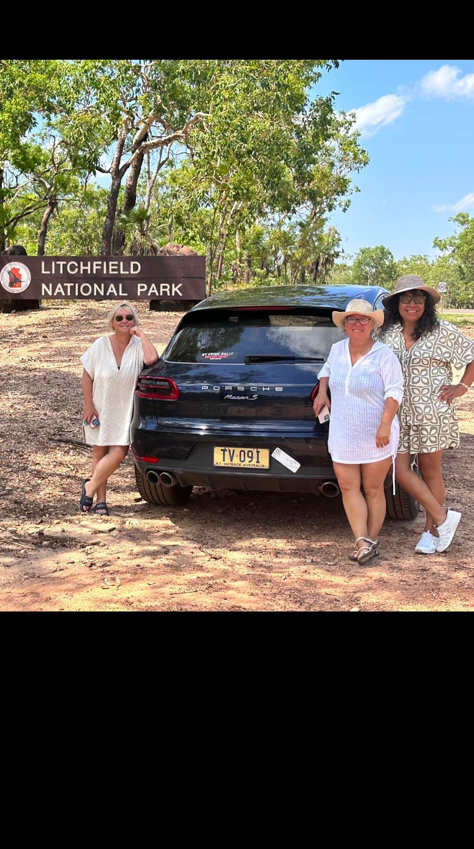 Three women pose near a black SUV at a park entrance — Litchfield VIP Tours In Darwin City, NT