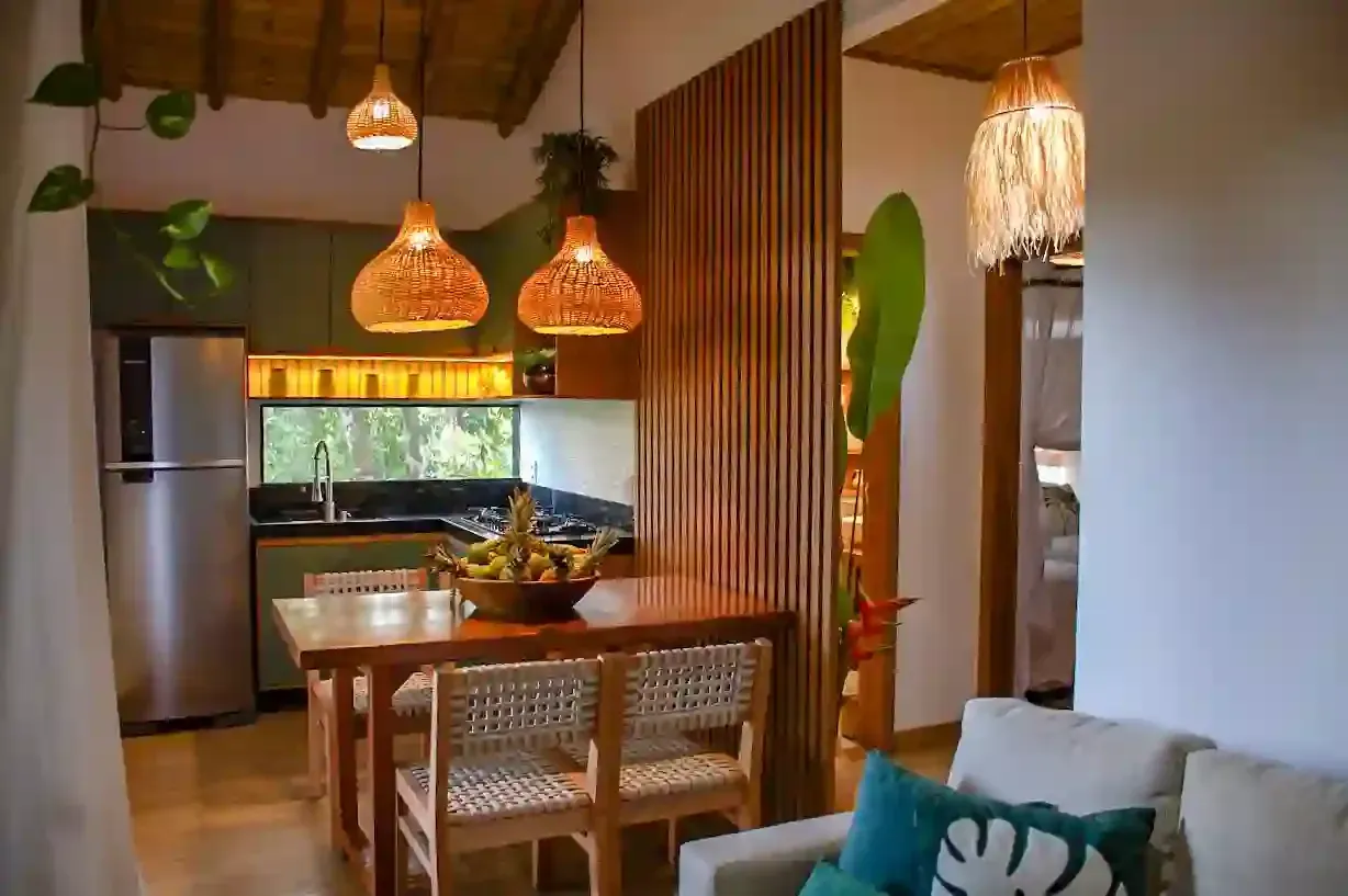 Uma sala de estar com um sofá, mesa, cadeiras e uma geladeira - pousada-recanto-caxando
