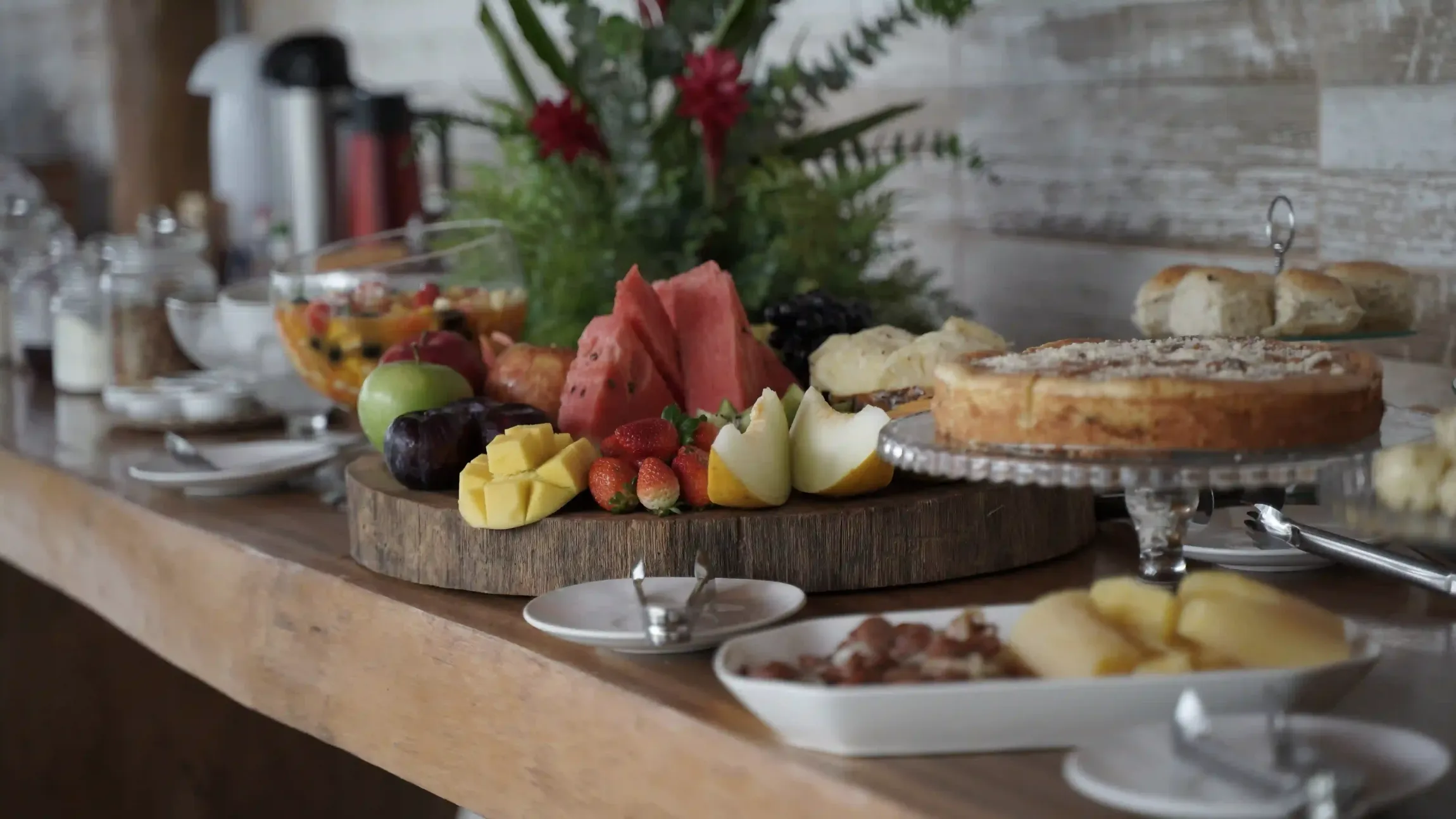 Uma mesa de madeira coberta com pratos de comida e frutas. pousada-recanto-caxando
