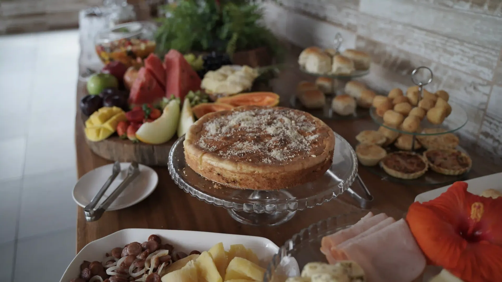 Uma mesa coberta com uma variedade de comidas, incluindo um bolo e frutas - pousada-recanto-caxando
