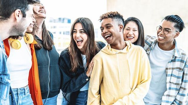 Group of young people laughing, gathered outdoors.