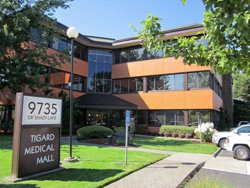 Tigard Medical Mall building exterior, 9735 SW Shady Ln, with orange facade, blue sky, and parking area.