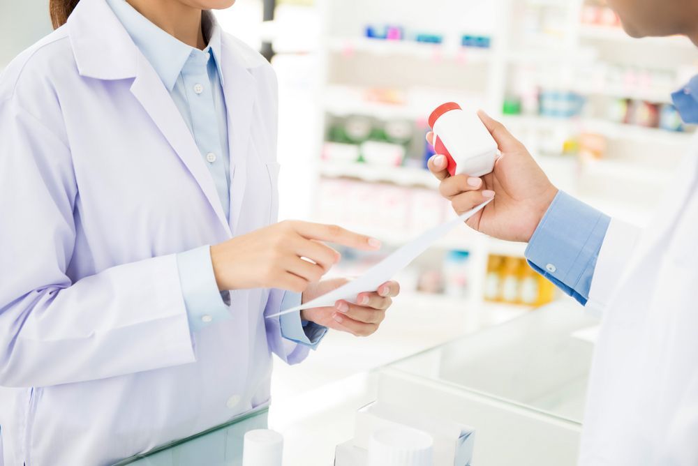 Pharmacists Holding Medicine Bottle And Discussing Prescription Drug In A Pharmacy Or Drugstore — Return Unwanted Medicines in Wulguru, QLD