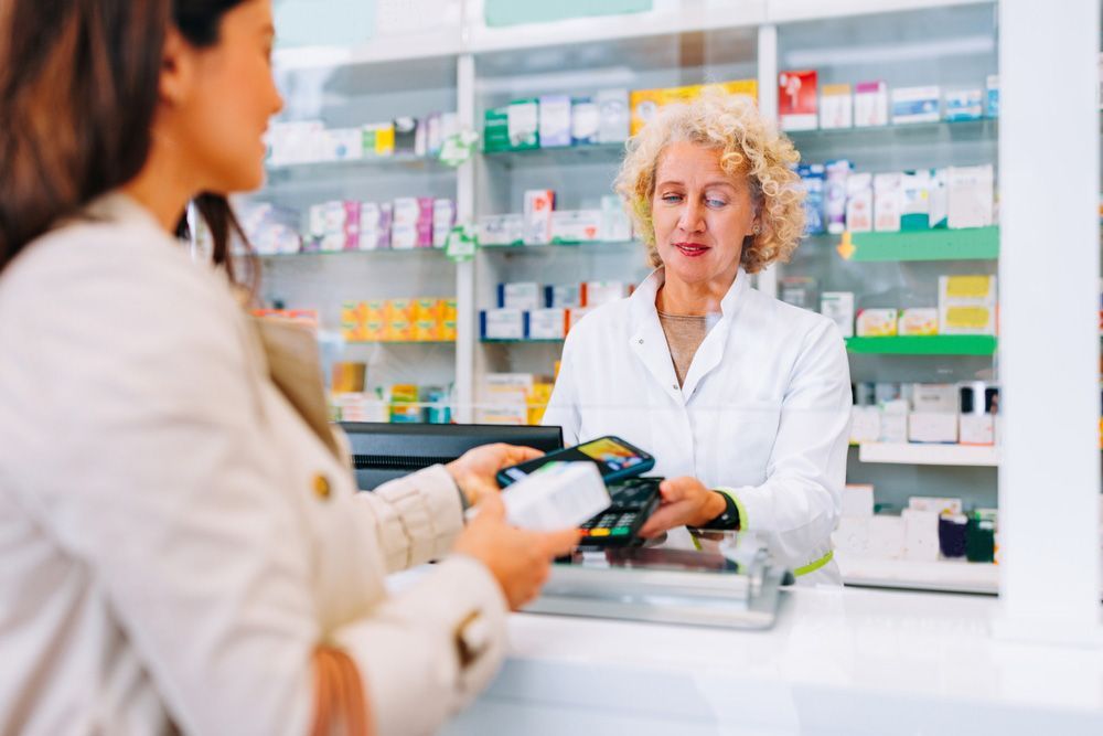 A Young Caucasian Woman Is Paying With Her Cellphone App At The Counter In The Pharmacy — Scripts on File & E-Scripts in Wulguru, QLD