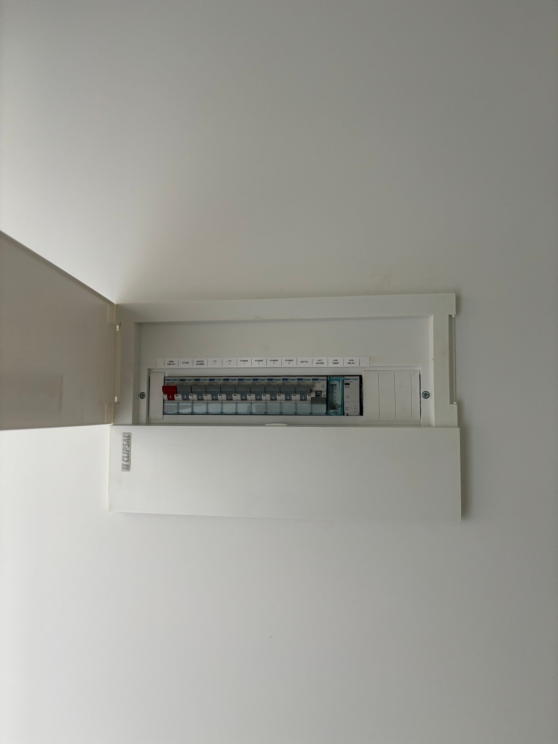 Open electrical breaker panel on a white wall with the cover door swung left — Anthony Cameron Electrical & Solar In Kepnock, QLD